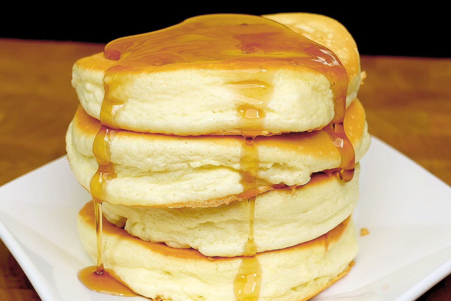 Fluffy banana pancakes stacked on a plate, topped with berries and syrup.