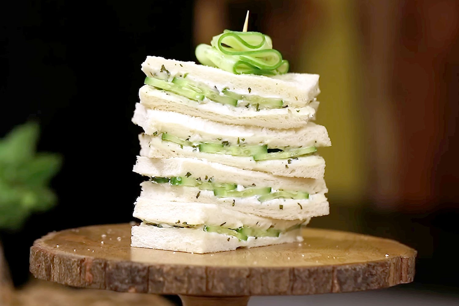 Two halves of a simple cucumber sandwich on white bread, showing thin cucumber slices and cream cheese.