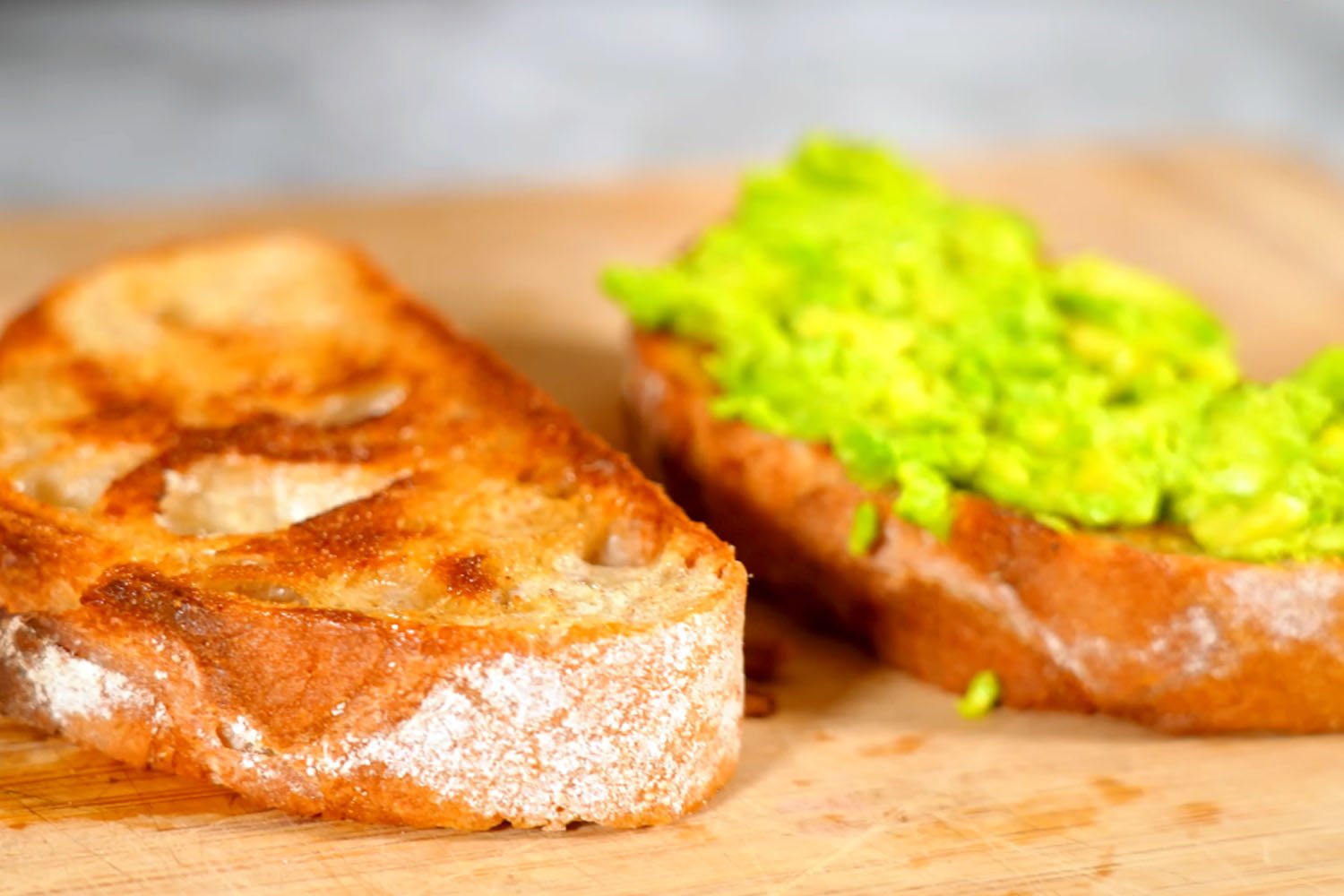 A close-up of a sandwich with mashed avocado on toasted bread, garnished with salt and pepper.